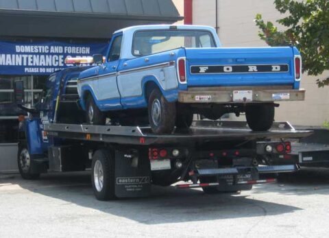 Classic car loaded on a flatbed tow truck